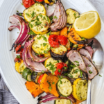 Colorful roasted vegetables, including carrots, zucchini, bell peppers, and sweet potatoes, coated with olive oil and cayenne pepper