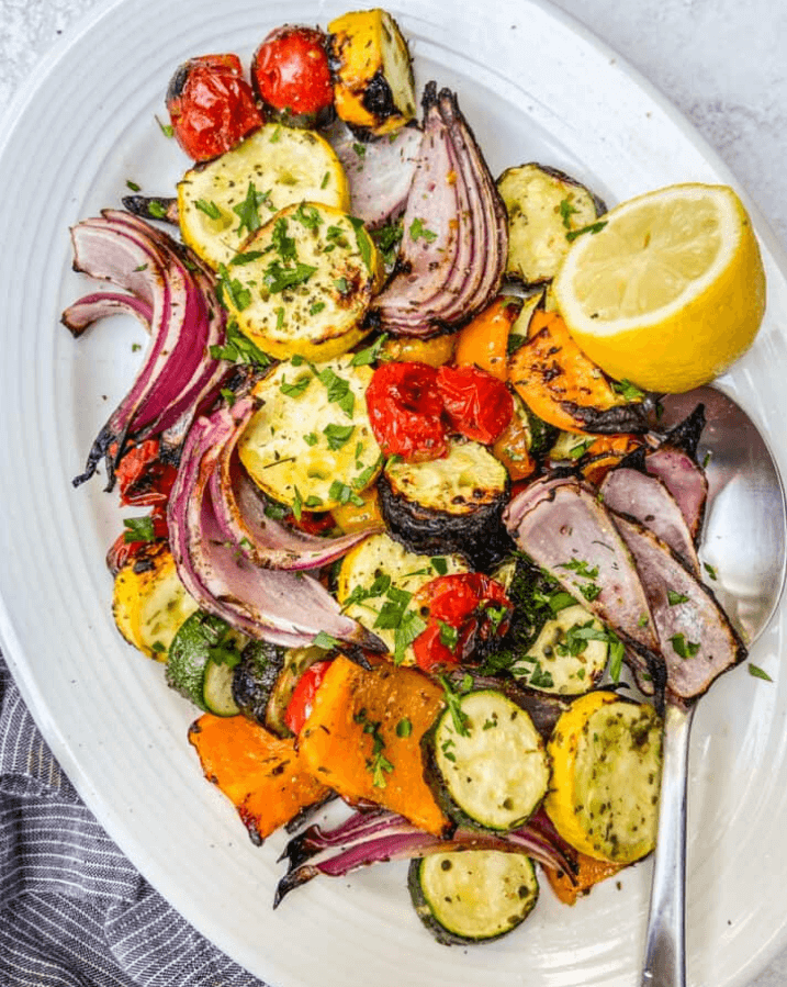 Colorful roasted vegetables, including carrots, zucchini, bell peppers, and sweet potatoes, coated with olive oil and cayenne pepper