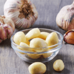 Fresh garlic bulbs and cloves on a wooden surface, showcasing their natural texture and earthy color