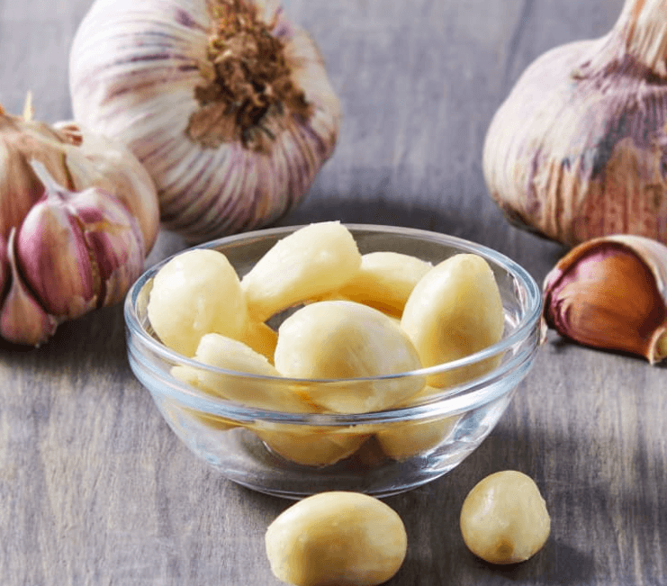 Fresh garlic bulbs and cloves on a wooden surface, showcasing their natural texture and earthy color