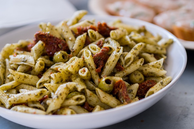 A plate of sun-dried tomato pasta garnished with fresh basil and Parmesan cheese, served on a rustic wooden table.